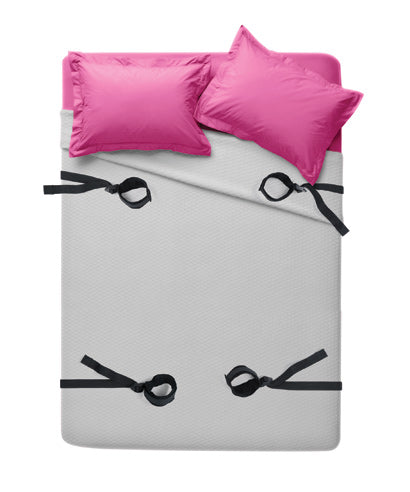 Bondage restraining set with pink cushions and black strap restraints on bed