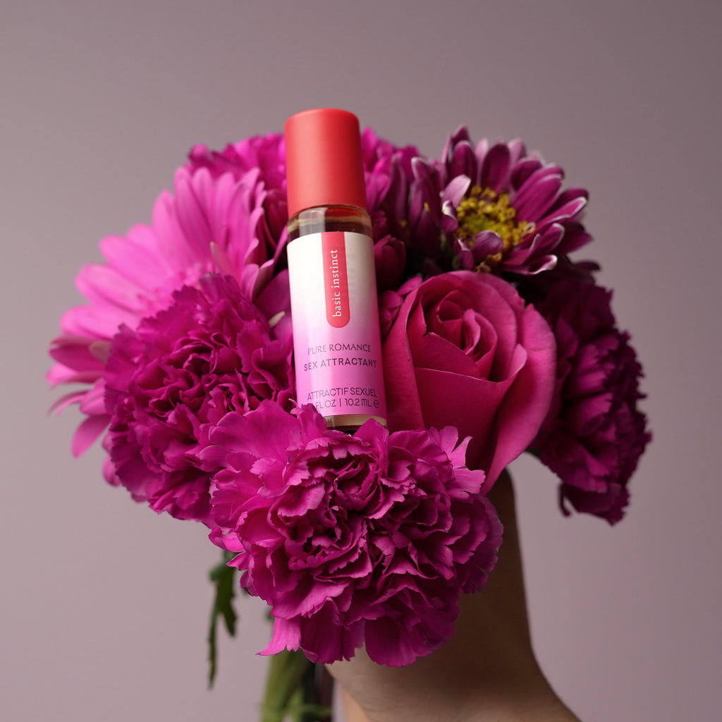 Basic Instinct sex attractant bottle with red cap, shown with bouquet flowers