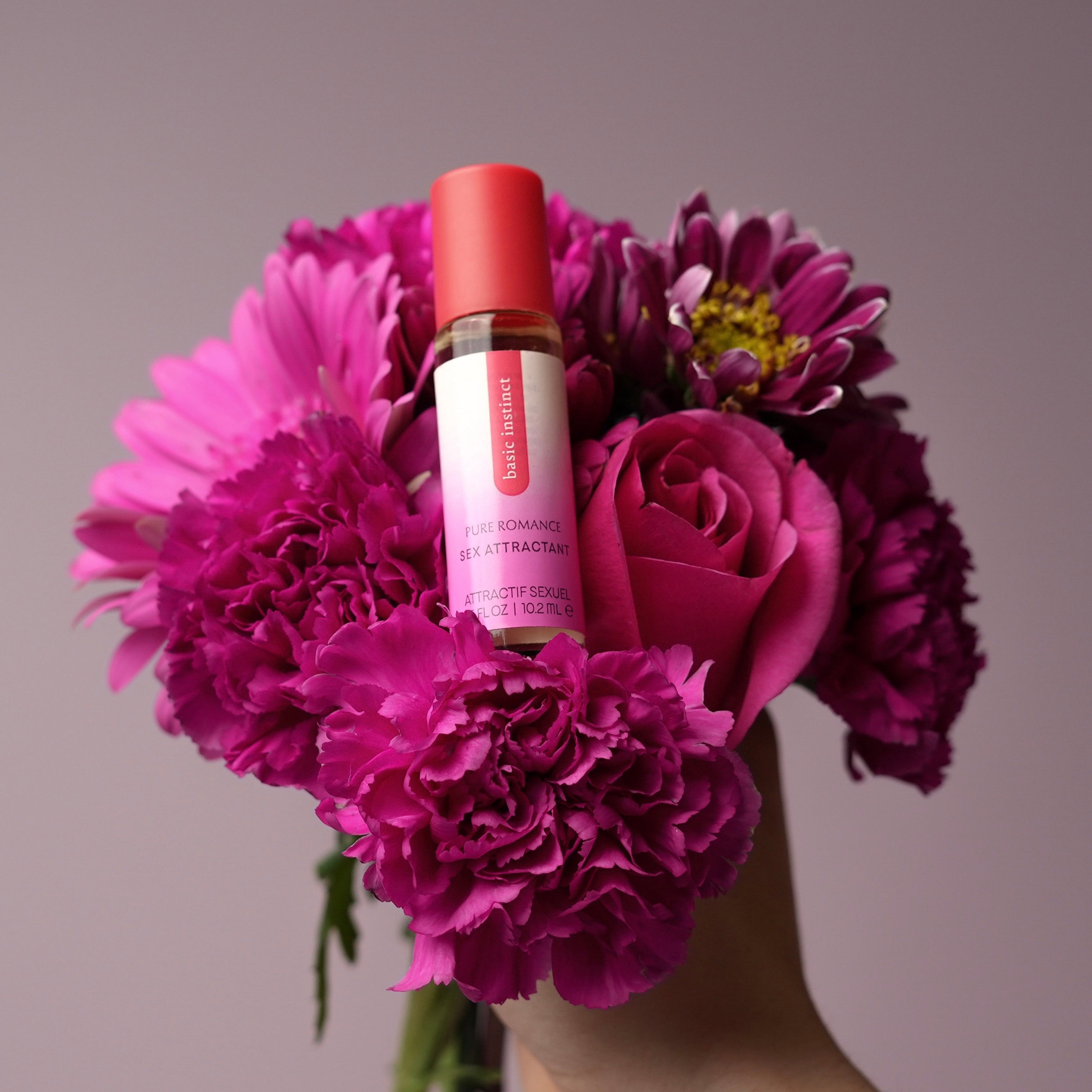 Basic Instinct sex attractant bottle with red cap, shown with bouquet flowers