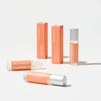 Pheromone roll-on perfume with silver cap, shown with matching orange boxes