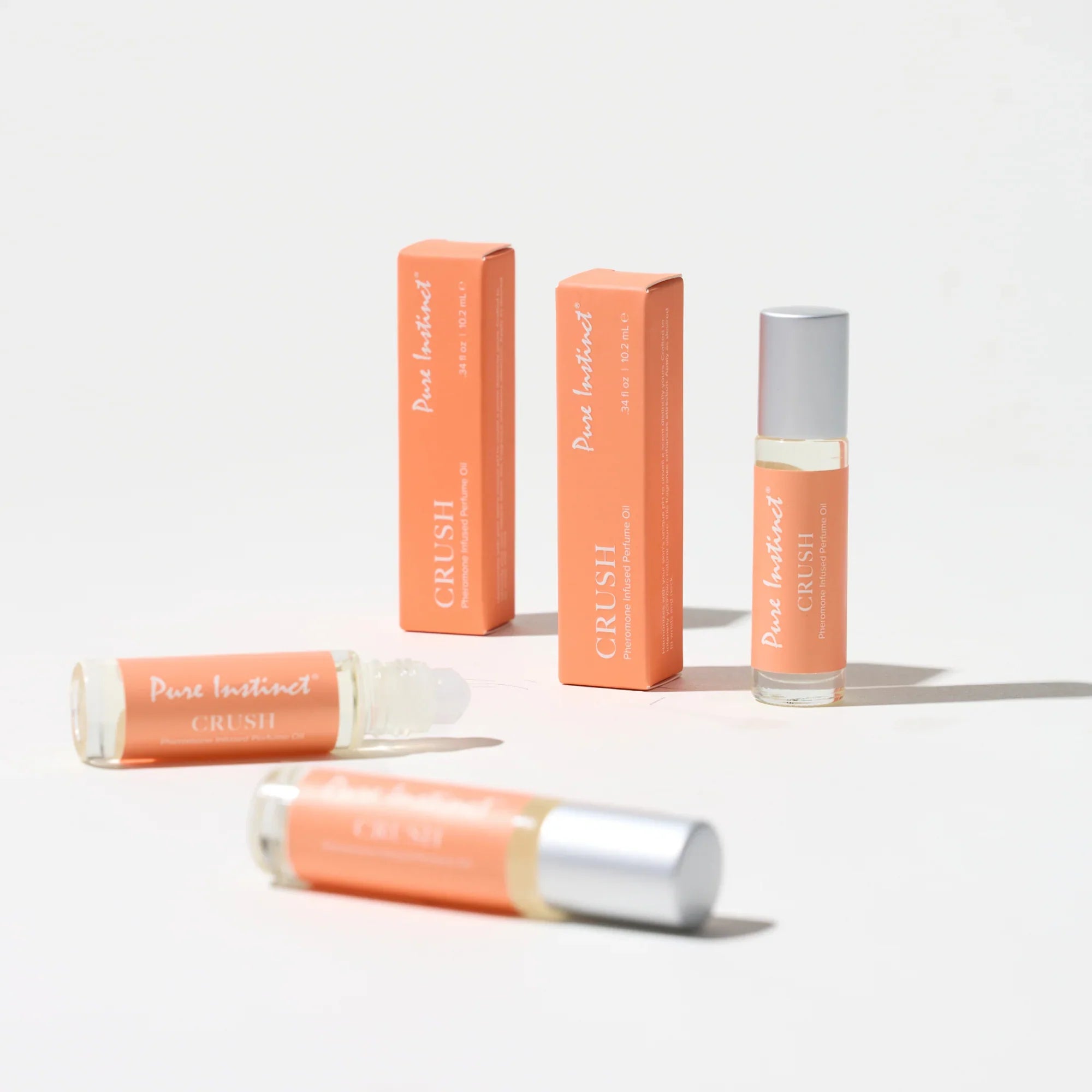 Pheromone roll-on perfume with silver cap, shown with matching orange boxes