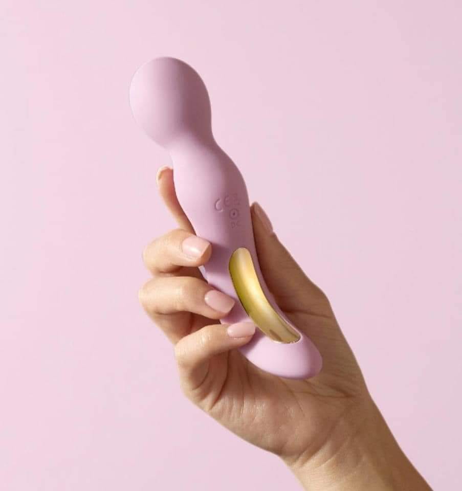 Curved pink silicone sex toy with gold accent and contoured handle