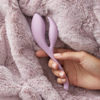 Light purple double-ended silicone massager on plush fabric, held by hand