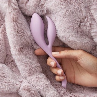 Light purple double-ended silicone massager on plush fabric, held by hand