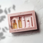 Mini fragrance set in rose-gold glitter box with four bottles and a rose-gold stick.