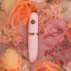 Pink lip-like applicator with rose-gold emblem and sparkling band detail.