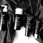 Uncovered Skincare Daily Essentials Kit tubes and bottles on dark cloth