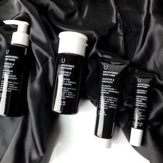 Uncovered Skincare Daily Essentials Kit tubes and bottles on dark cloth