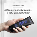 Hand holding black tingling sexual cream tube with blue REv lettering