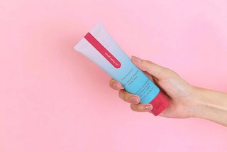 Deodorant tube held in hand, red cap and blue body