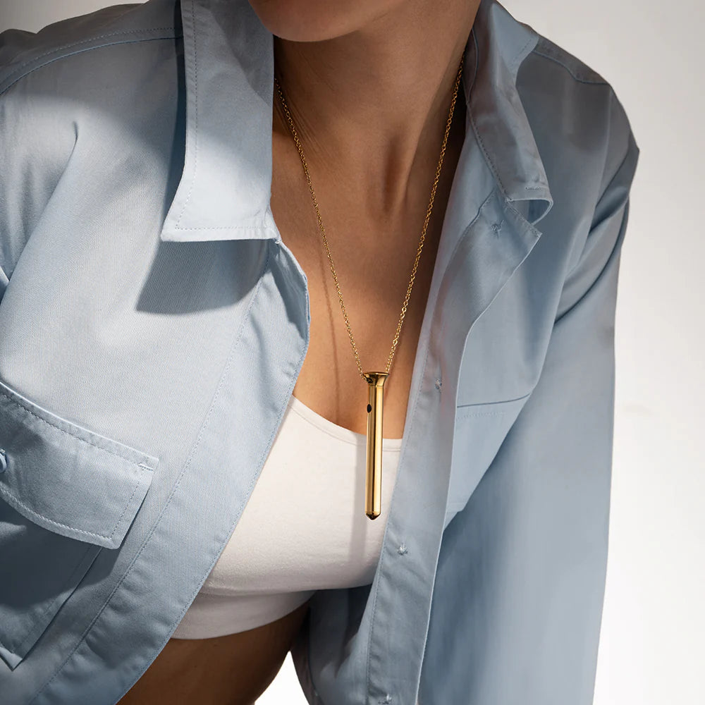 Gold bar pendant necklace worn on a neckline