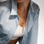 Gold bar pendant necklace worn on a neckline
