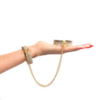 Rhinestone handcuffs with gold chain draped between wrists