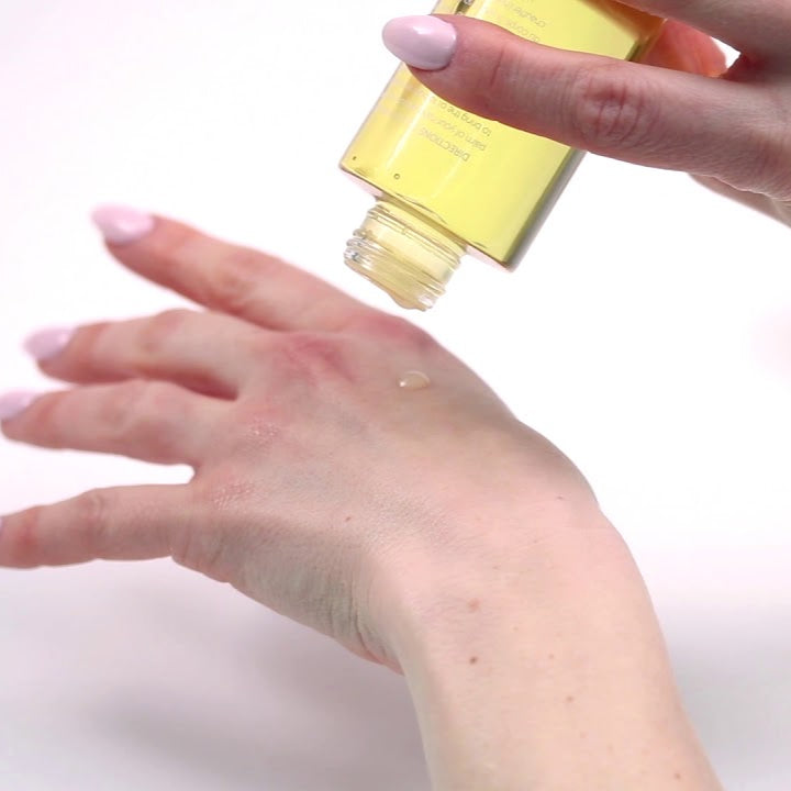 Hands applying High Love massage oil from a tipped bottle onto skin