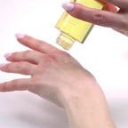 Hands applying High Love massage oil from a tipped bottle onto skin