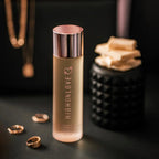 High Love massage oil bottle with rose-gold cap, beside small decorative beads