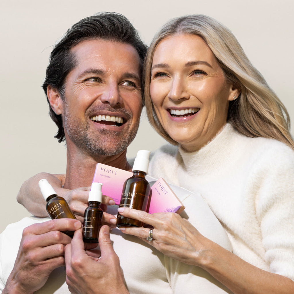 Intimacy set with amber oil bottles and pink packaging held by a smiling couple