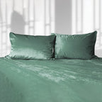 Green liquid velvet sheet and two matching pillowcases, made bed set with velvet sheen.