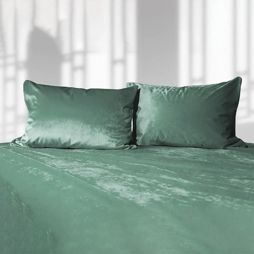 Green liquid velvet sheet and two matching pillowcases, made bed set with velvet sheen.