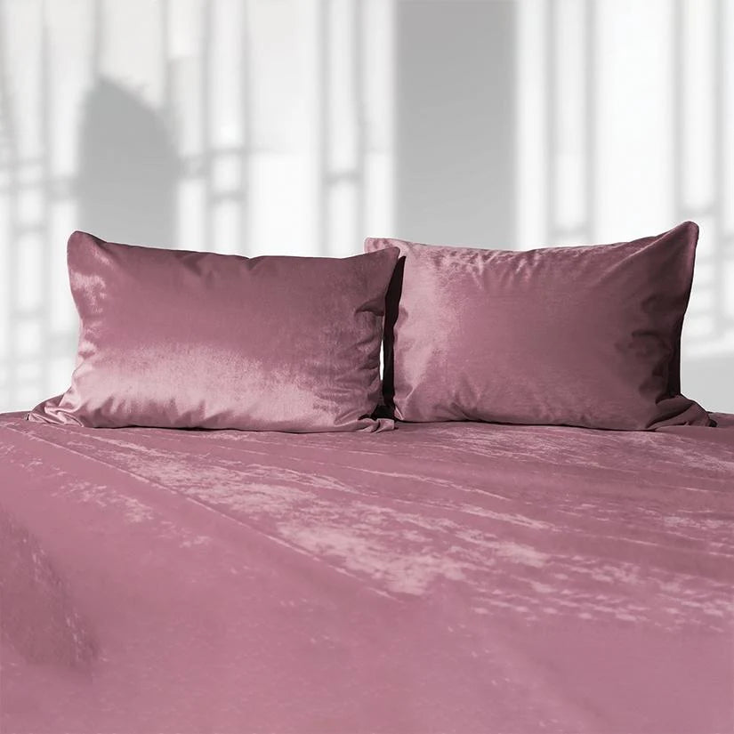 Pink liquid velvet sheet with two matching pillowcases, shown as a made bed set.