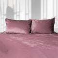 Pink liquid velvet sheet with two matching pillowcases, shown as a made bed set.
