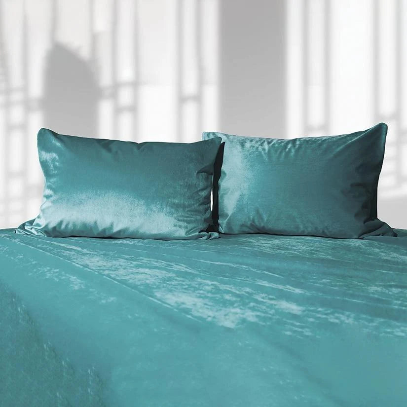 Teal liquid velvet sheet and two matching pillowcases, made bed set with shimmering finish.