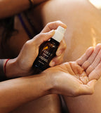 Small amber oil bottle being applied to bare skin with fingertips