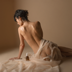 Amber massage oil bottle on bedding with bare shoulders and hands nearby