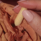 Hand holding a pale yellow CBD suppository near skin