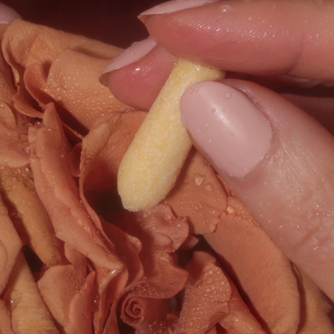 Hand holding a pale yellow CBD suppository near skin
