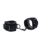 Black velvet handcuffs with chain and two cuff pads, angled close-up.
