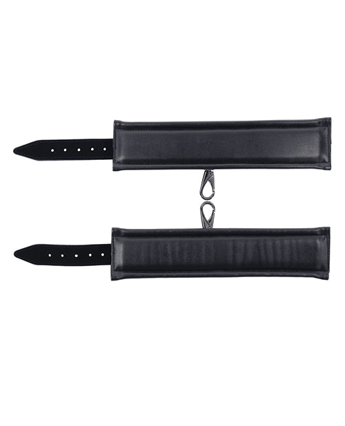 Black cuff straps with rows of holes and metal ring dangles, flat lay.