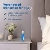 Blue intimate lubricant bottle on bedside table beside flowers and pillows