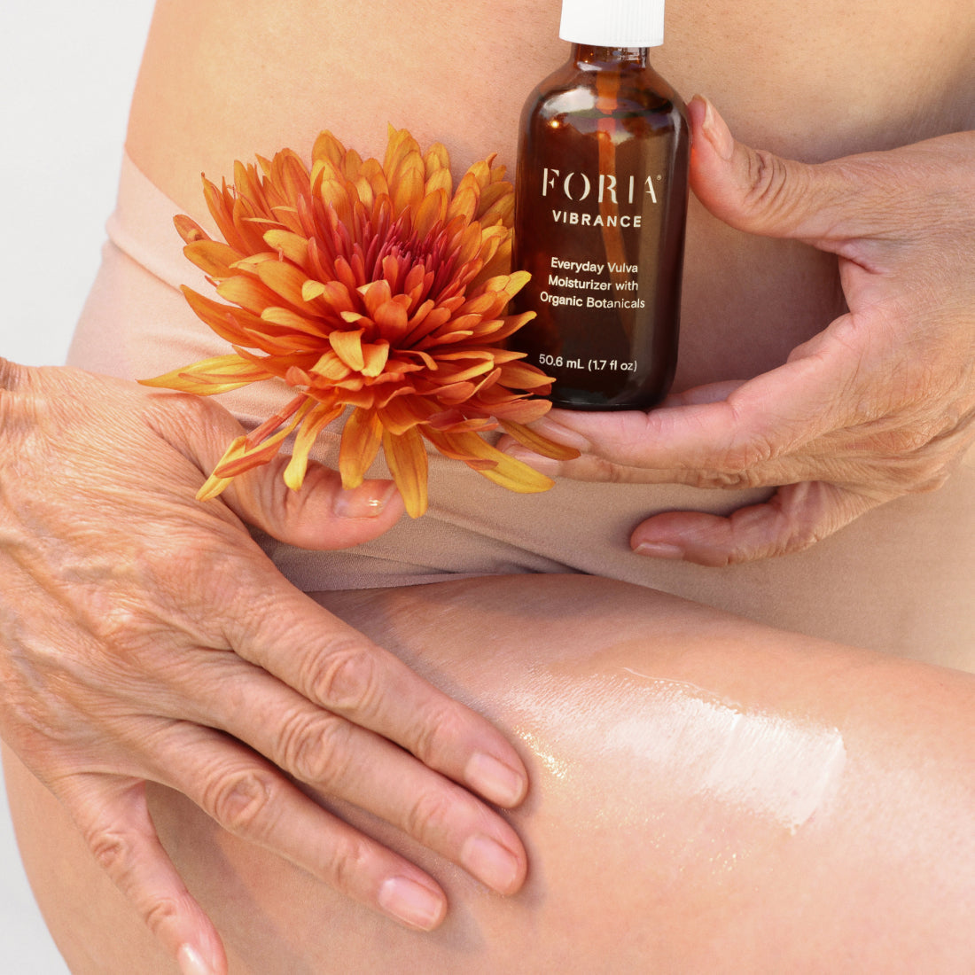 Vulva moisturizer bottle held near hands applying lotion