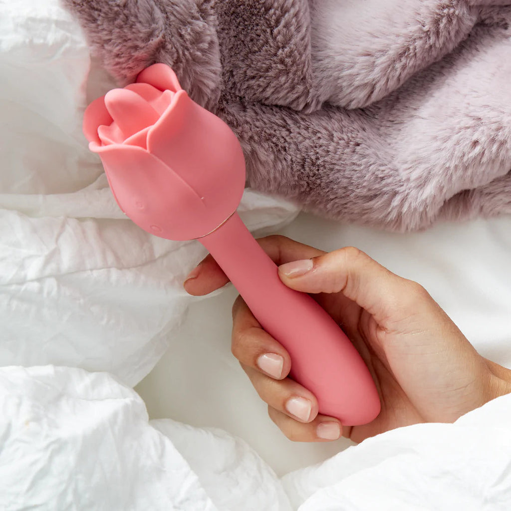 Pink rose-shaped massager with petal-like head, handheld in a hand