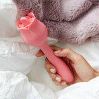 Pink rose-shaped massager with petal-like head, handheld in a hand