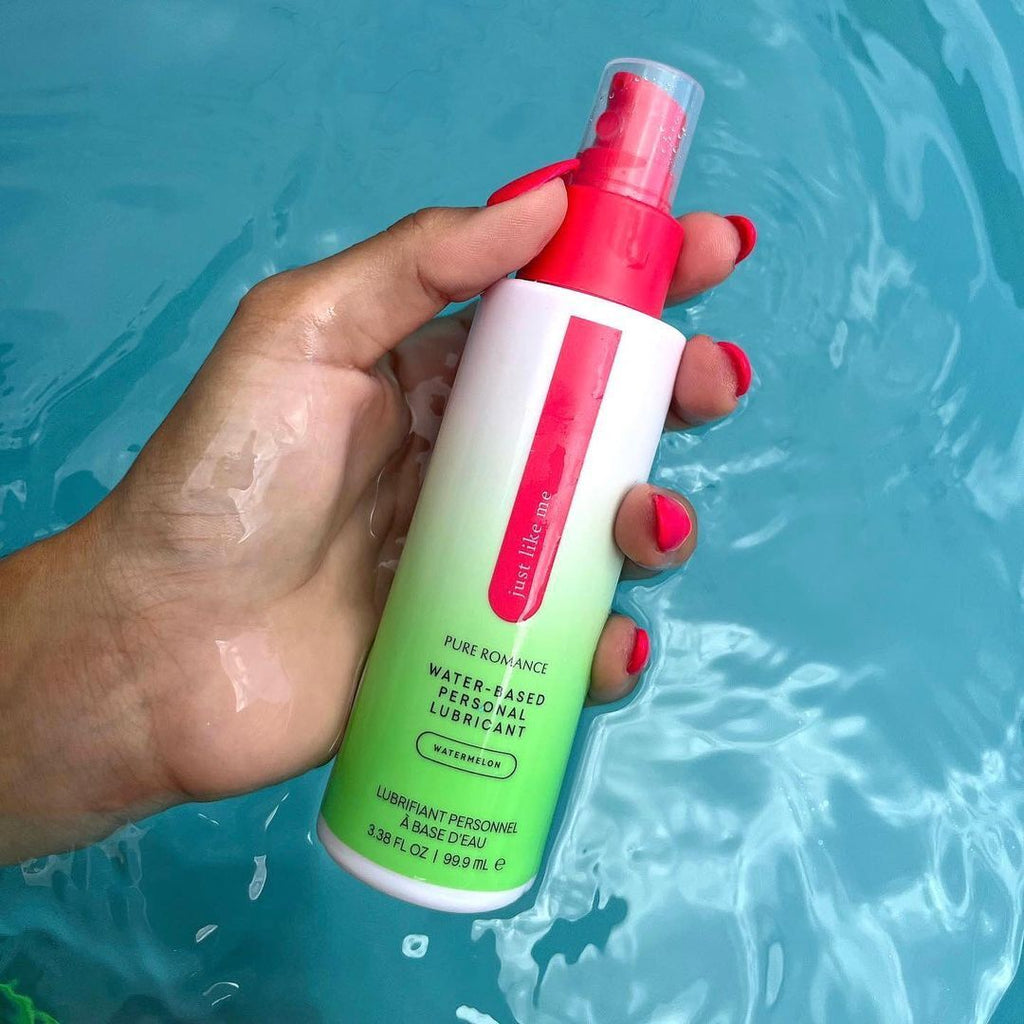 Hand holding water-based personal lubricant bottle with pink pump, translucent green bottle