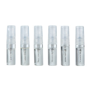 Row of clear fragrance travel spray bottles with printed labels and small caps