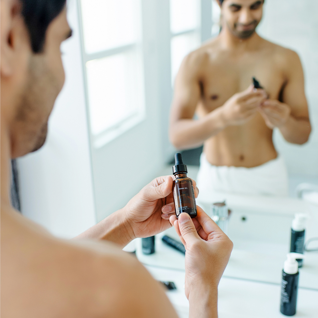 Beard oil bottle with black dropper held for applying Atlas beard oil