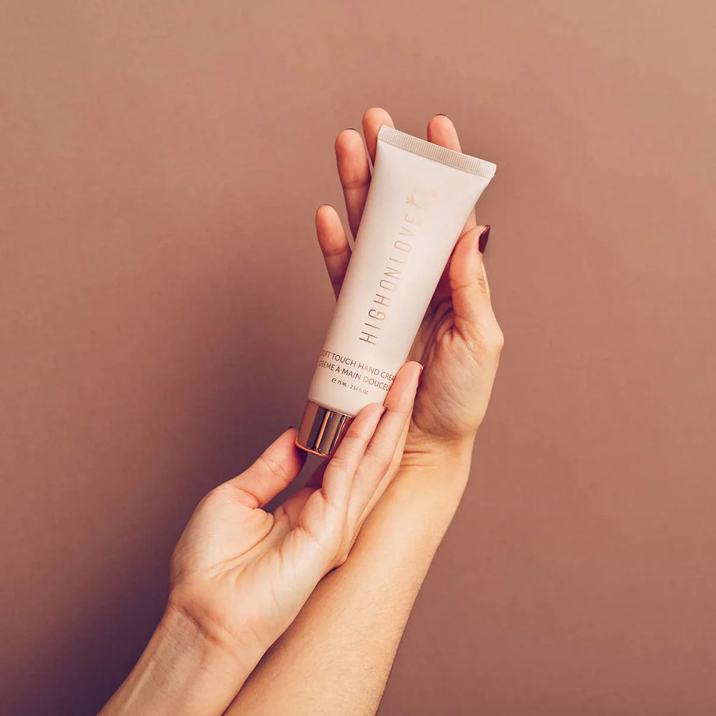 Hands holding a light pink hand cream tube with metal base