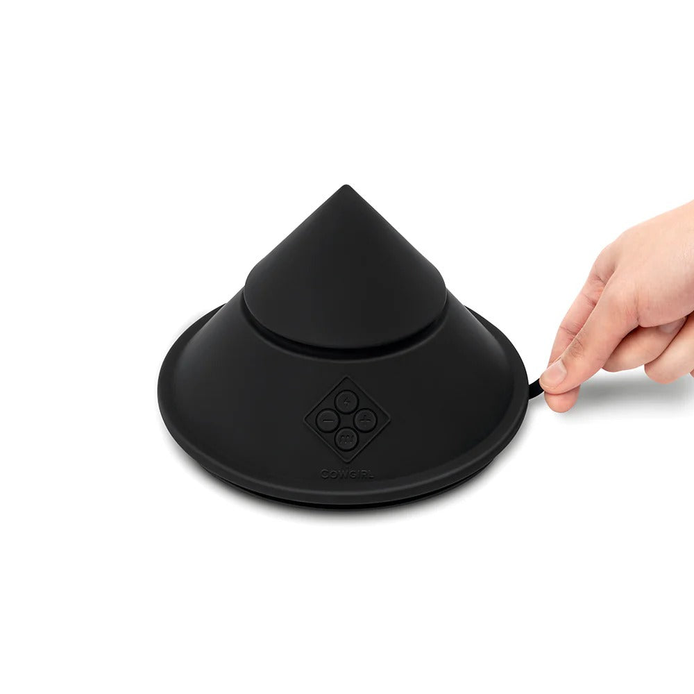 Black cone-shaped sex massager with base emblem, hand gripping the side