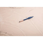 Vibrating feather tickler resting on satin sheet, navy feather tip, pink handle