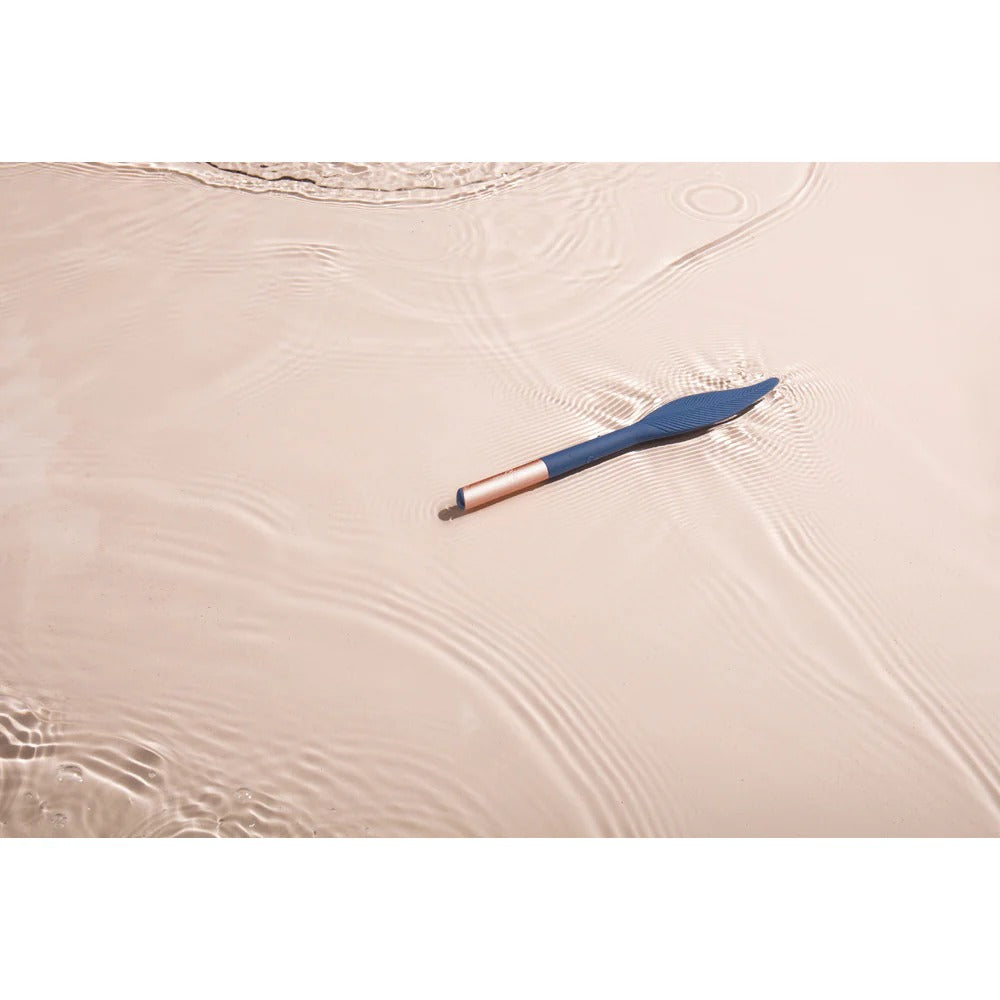 Vibrating feather tickler resting on satin sheet, navy feather tip, pink handle