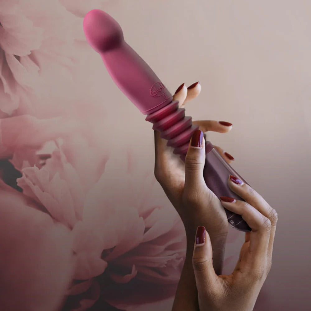 Pink thrusting vibe held in hand with ribbed handle and rounded tip.