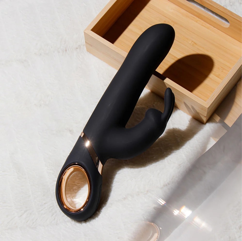Black G-spot vibrator on floor near wooden box, curved arms and rose-gold motor ring