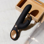 Black G-spot vibrator on floor near wooden box, curved arms and rose-gold motor ring