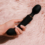 Dual-ended vibrator held in hand with dark silicone and rose-gold detail band