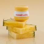 Pineapple-flavored lip balm jar on stacked pineapple slices