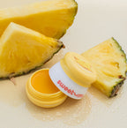 Pineapple-flavored lip balm jar with open lid on pineapple slices